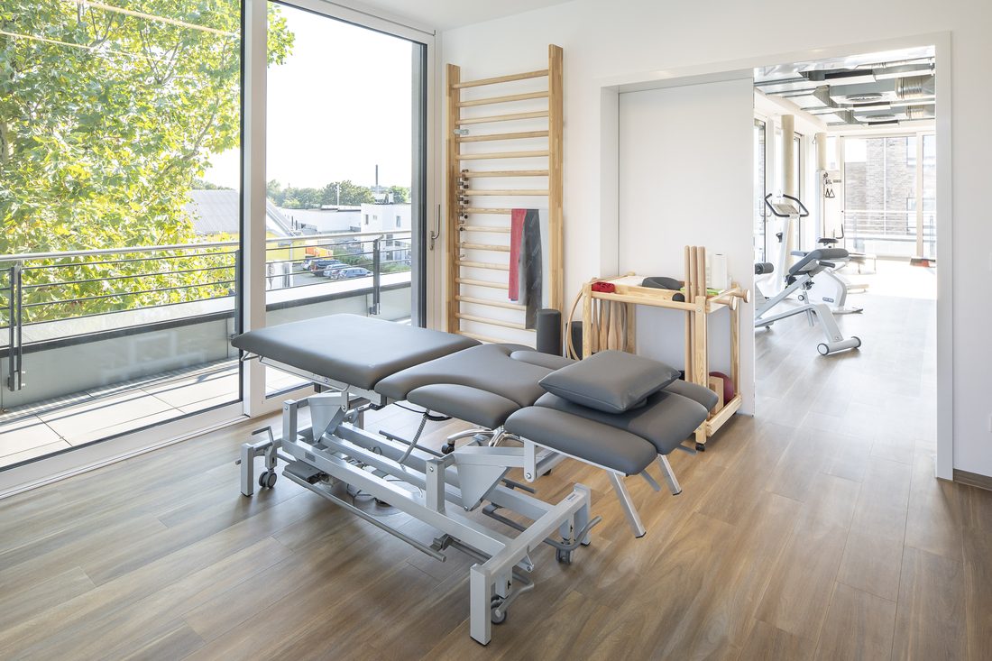 Physiotherapie-Behandlungsraum mit Liege und Sprossenwand